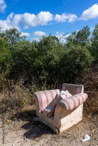 Man's disregard for nature: a sofa abandoned in the middle of a field, showcasing a lack of environmental consciousness. photo