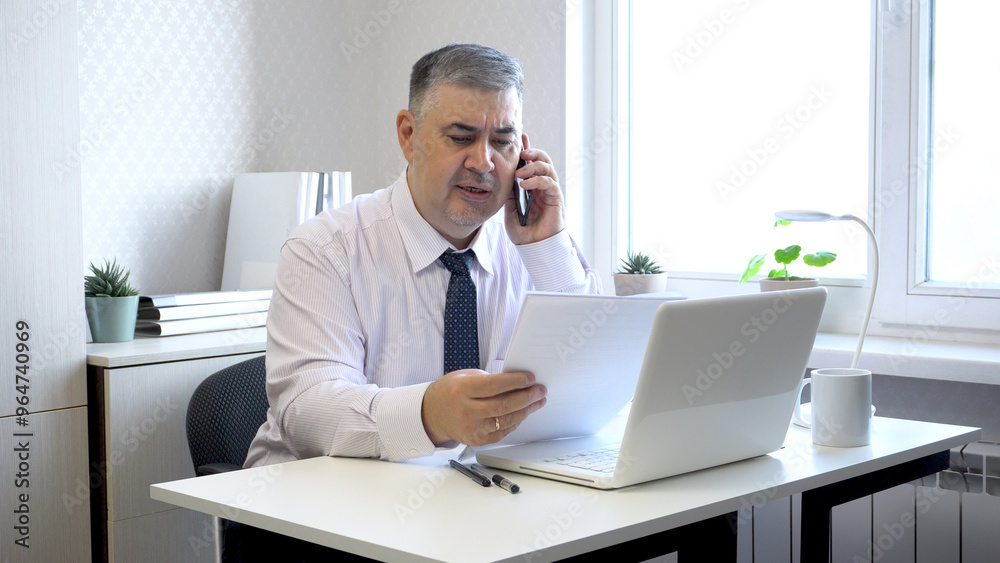 Man Working with Documents and Talking on Phone in Office Man Working with Documents and Talking on Phone in Office