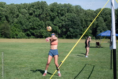 Female volleyball player setting her partner during a summer day grass doubles tournament