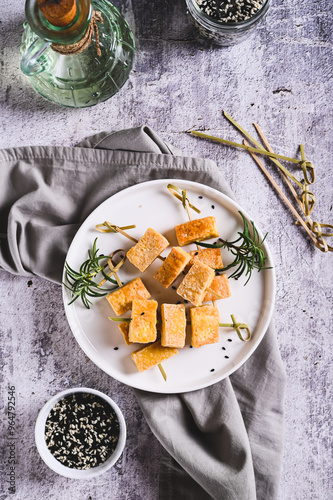 Obraz na płótnie Pieces of delicious fried tofu soy cheese on skewers on a plate on the table top and vertical view w salonie