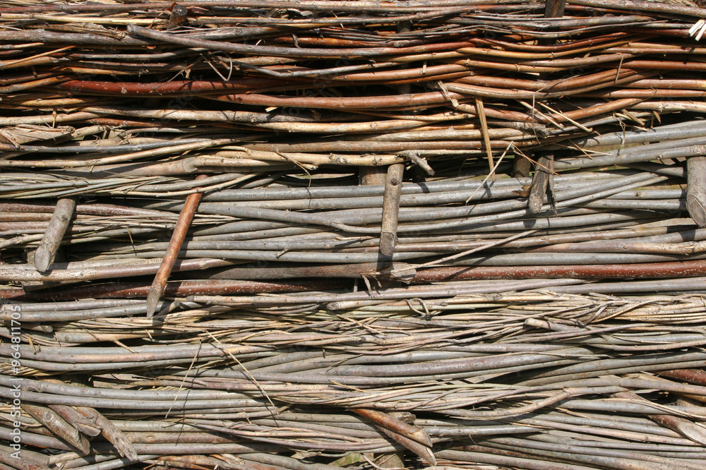 Wicker fence with tree branches texture close up. Sturdy wattle fence, continuously woven willow fence. Organic material, brushwood weaving barrier crafting Wicker fence with tree branches texture close up. Sturdy wattle fence, continuously woven willow fence. Organic material, brushwood weaving barrier crafting