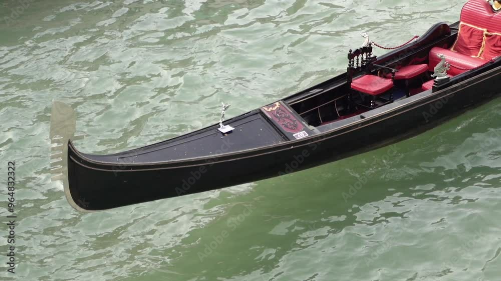 A luxurious black gondola parked on a canal with no people inside. A luxurious black gondola parked on a canal with no people inside.