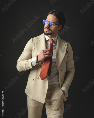 Принти на полотні relaxed young man in beige suit fixing his red tie