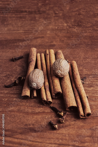 fragrant cinnamon sticks, nutmeg and clove buds on a wooden background close-up, top view