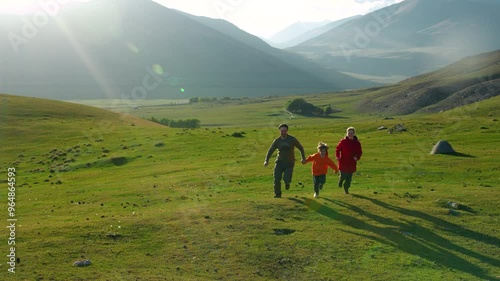Happy family running in high mountains on summer day, slow motion