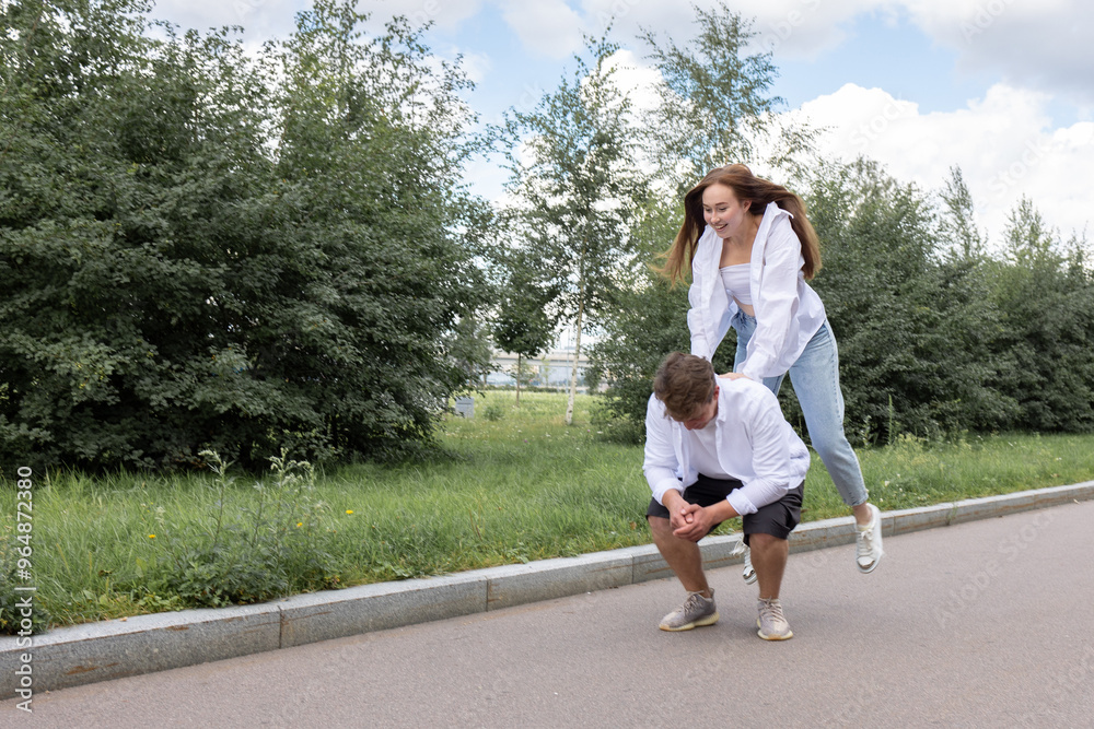 Loving couple of young girl and man are walking and having fun in park on warm summer day. High quality photo