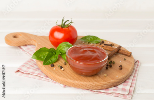 Delicious ketchup with spices and tomatoes on wooden table