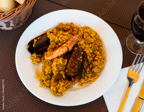 Popular dish of Spanish cuisine paella with seafood, made from rice, supplemented with saffron, squid, shrimp and mussels photo