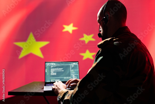 Chinese engineer making bot accounts spreading conspiracy theories online to discredit Western powers. IT specialist working for China military intelligence coding troll farm promoting communism photo