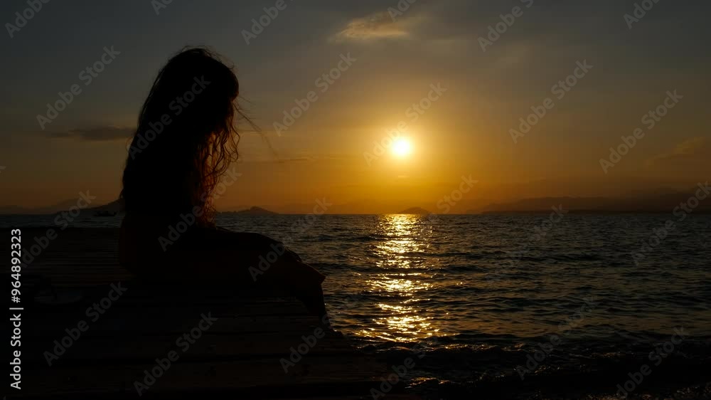 Child sit on pier admiring evening. A little girl silhouette enjoy the time by the lake during golden evening time. Child sit on pier admiring evening. A little girl silhouette enjoy the time by the lake during golden evening time.