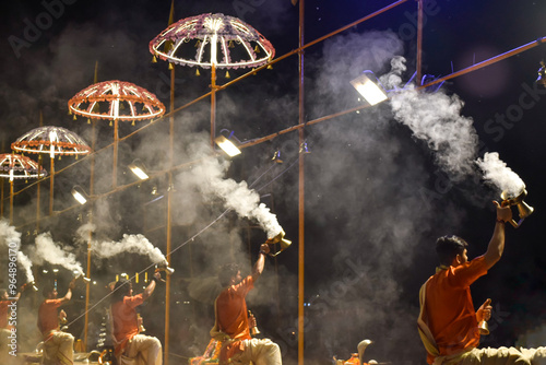 Pujaris or Indian priests performing Aarti ceremony on banks of Ganges in crowd photo