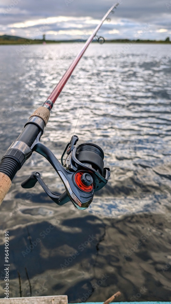 Hand holding fishing rod and reel, fishing at Corrib river at Galway, Ireland, spinning, angling, catch and release, sport and leisure, nature background