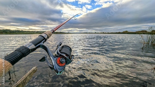 Obraz na płótnie Hand holding fishing rod and reel, fishing at Corrib river at Galway, Ireland, spinning, angling, catch and release, sport and leisure, nature background w salonie