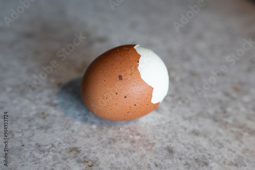Fotografía Boiled Egg with Partially Removed Speckled Shell, Revealing White Surface