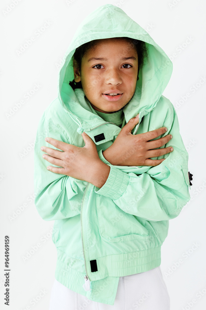Stylish young boy in green jacket and white pants strikes a pose against white backdrop Stylish young boy in green jacket and white pants strikes a pose against white backdrop