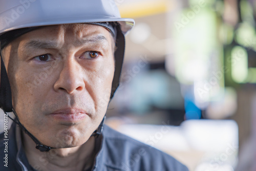 Supervisor of a manufacturing site wearing a white helmet with a machine tool in the background.