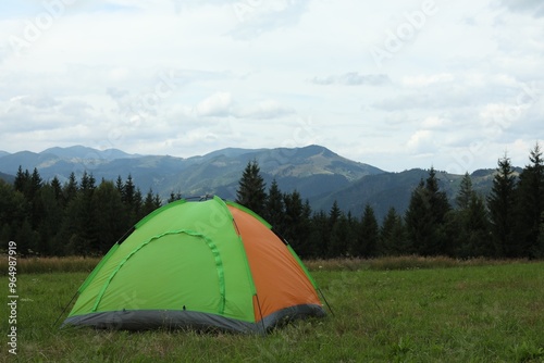 Tent on green grass in mountains, space for text