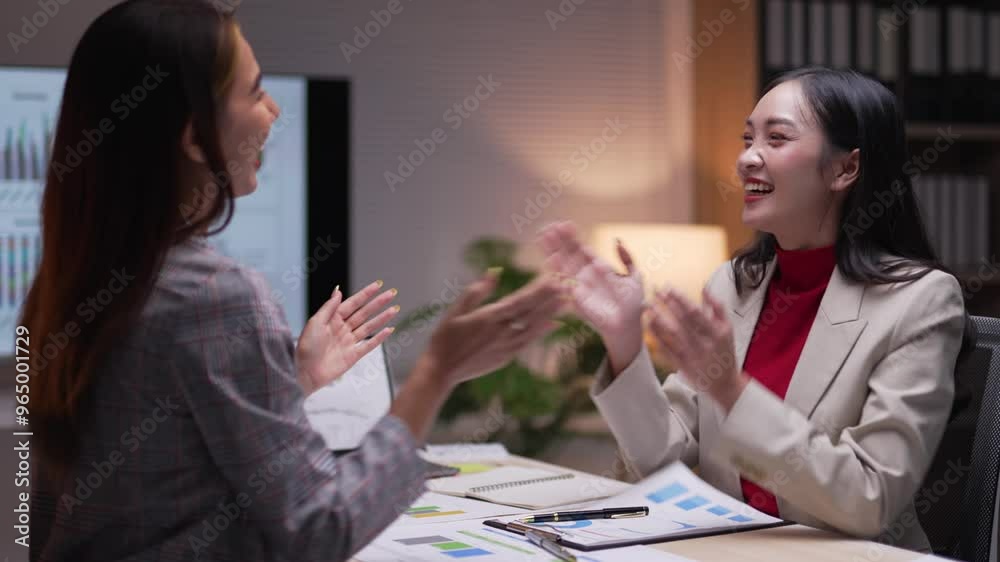 Two businesswomen shake hands and clap in celebration after successfully closing a deal during an office meeting, showcasing teamwork and professional achievement Two businesswomen shake hands and clap in celebration after successfully closing a deal during an office meeting, showcasing teamwork and professional achievement