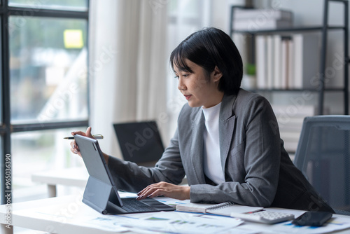 Asian businesswoman working with digital tablet and stylus analyzing financial data photo