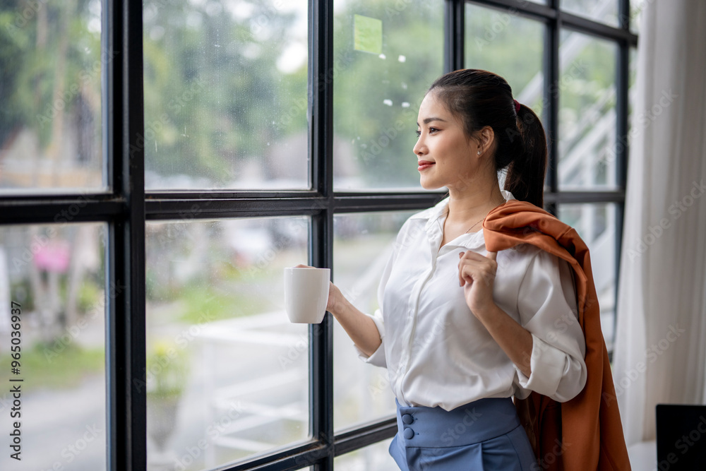 Businesswoman holding coffee cup and looking through the window in office Businesswoman holding coffee cup and looking through the window in office