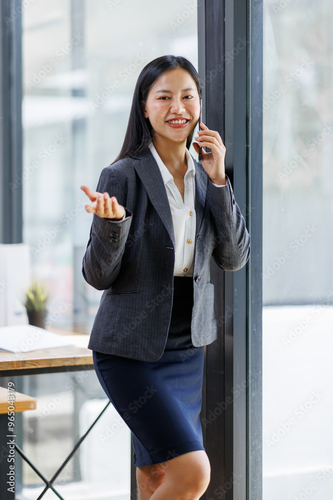 Asian woman entrepreneur busy with her work in the office. Smiling business asian woman texting, using smart phone in office while planning sales, research or financial strategy in company. Asian woman entrepreneur busy with her work in the office. Smiling business asian woman texting, using smart phone in office while planning sales, research or financial strategy in company.