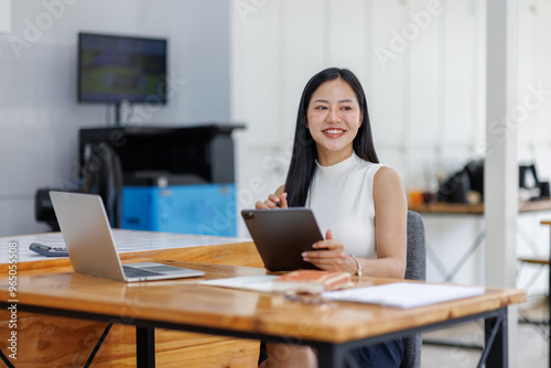 Business asian woman or female worker using a laptop computer to analyse her financial data.business people research or financial strategy in company concept. Laptop white screen mockup.