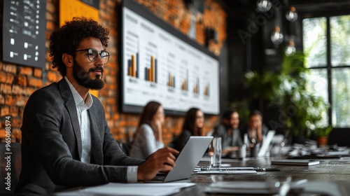 Strategic Visionary: A focused young entrepreneur analyzes data in a modern office, his team collaborating in the background. 