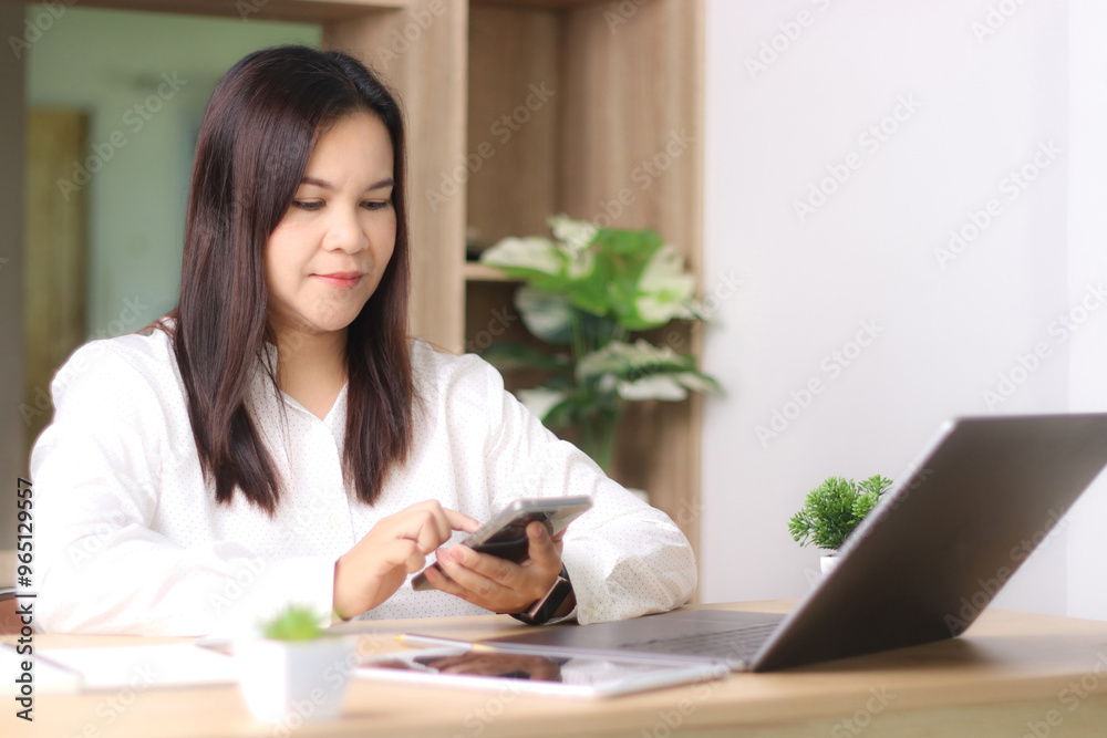 Young woman typing text message on smart phone. Asian woman in casual wear sitting at a table using mobile phone. Young woman typing text message on smart phone. Asian woman in casual wear sitting at a table using mobile phone.
