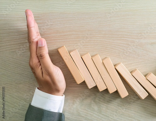 the hand of a businessman stopping a series of falling wooden blocks or dominoes. generative ai photo