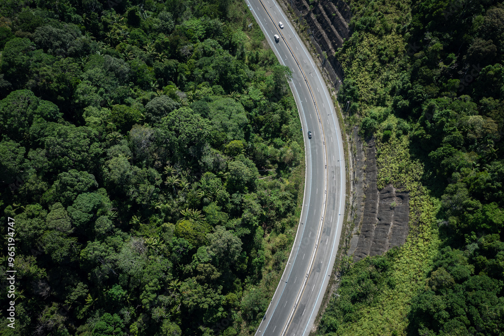 Fototapeta premium Aerial view of asphalt road with cars through green forest woods and mountain, Trang, Thailand.
