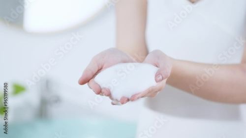 Wallpaper Mural Close-up of woman showing smooth white foam in her palm. Behind is a wall mirror and sink, a modern bathroom setting. Advertising video for facial cleanser Torontodigital.ca