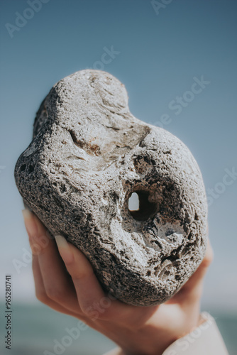 Hühnergott, Hand hält Stein mit Loch am Strand photo