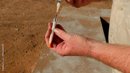 Caucasian veterinarian injects syringe with drugs for dart gun, South Africa