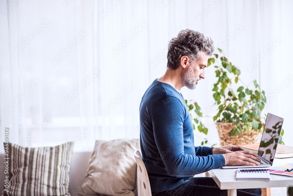 Fototapeta premium Side view of man working on computer from home. Telecommuting, homeoffice for handsome man. with copy space.