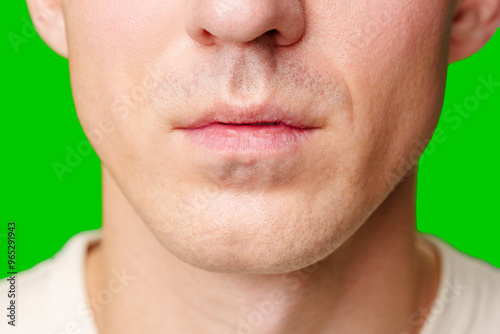 Close-Up of a Young Man's Face With Green Background Displaying Distinct Expression