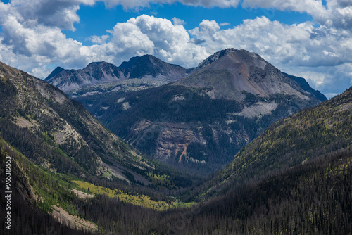 mountain forest valley with distant peaks and afternoon summer clouds