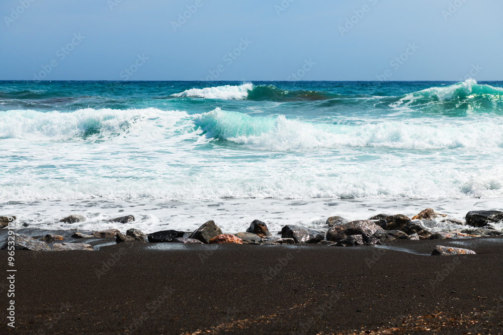 Santorini island, Greece. Waves on the beach. Perissa beach with black volcanic sand.