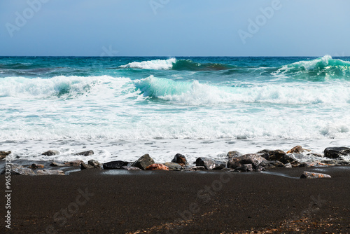 Santorini island, Greece. Waves on the beach. Perissa beach with black volcanic sand.