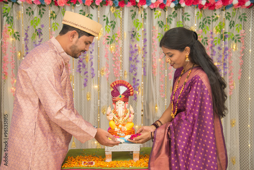 Happy Indian couple Family celebrating Lord Ganesh Festival, Worshipping God together in traditional wear at home, seeking blessings from Lord Ganesha, Pune, Maharashtra, India. photo