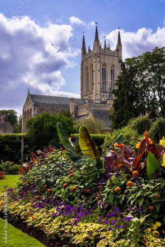 Tall standing Abby with blue sky and white clouds and flowers in the foreground photo