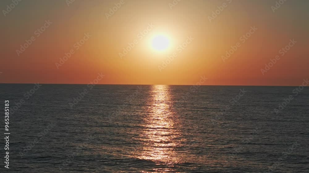 Flying over the sea at sunrise, orange sun on the horizon, casting light on the waves. Aerial shot in slow motion. Flying over the sea at sunrise, orange sun on the horizon, casting light on the waves. Aerial shot in slow motion.