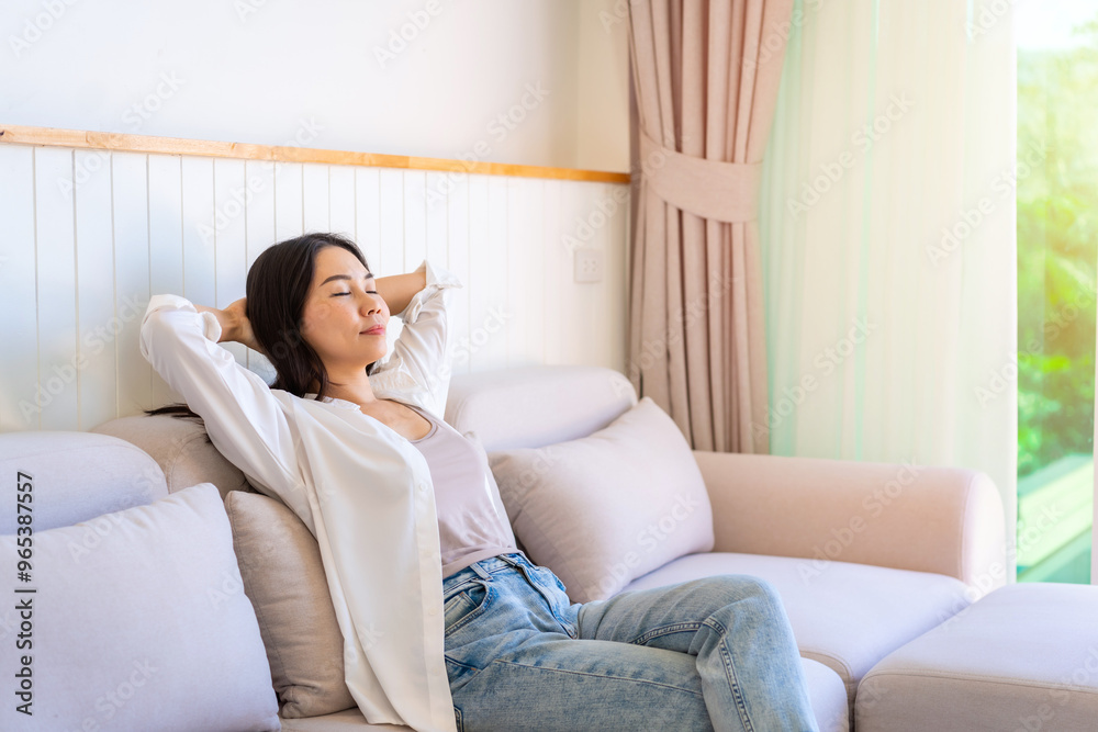 Carefree Asian woman relaxing and sitting on a sofa at home in the morning Carefree Asian woman relaxing and sitting on a sofa at home in the morning