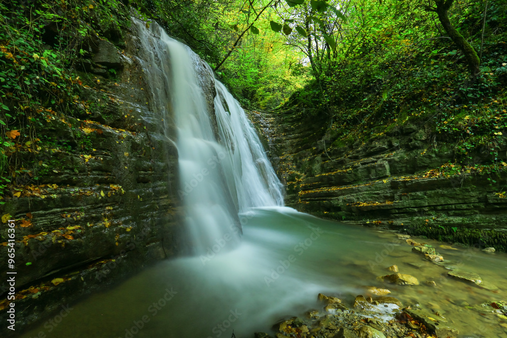 Obraz premium image of waterfall, lake and rock formations among autumn colors.