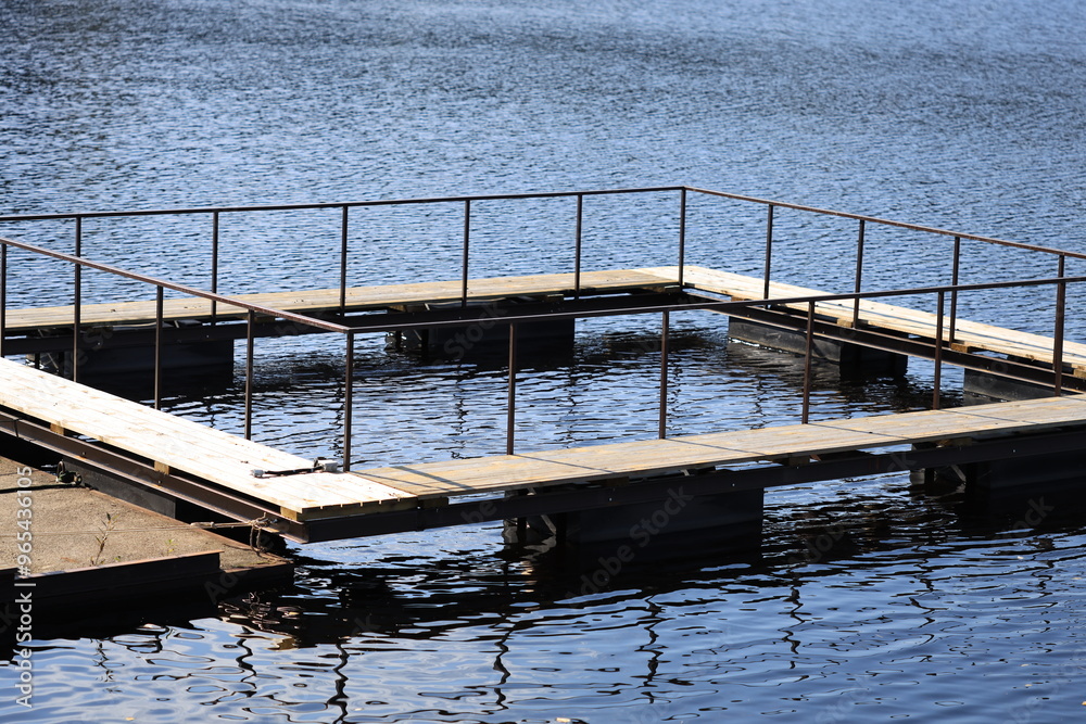 A wooden dock extends into a lake with calm waters, suitable for boating or fishing. A wooden dock extends into a lake with calm waters, suitable for boating or fishing.