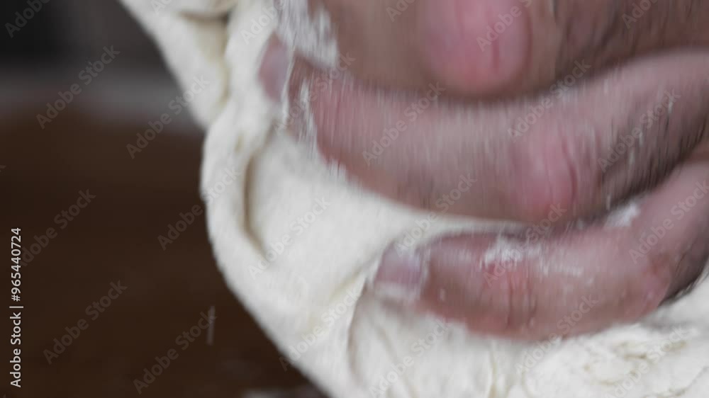Male hands knead dough on a pastry board, possibly for pizza or another dish. Flour is sprinkled, and the dough is worked thoroughly in a real home kitchen. Male hands knead dough on a pastry board, possibly for pizza or another dish. Flour is sprinkled, and the dough is worked thoroughly in a real home kitchen.