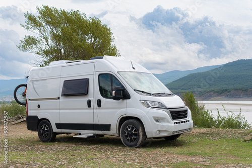 modern camper van for vacations by a lake and mountains motorhome trip with bicycles. retractable step down windows folding plates and cooler. photo