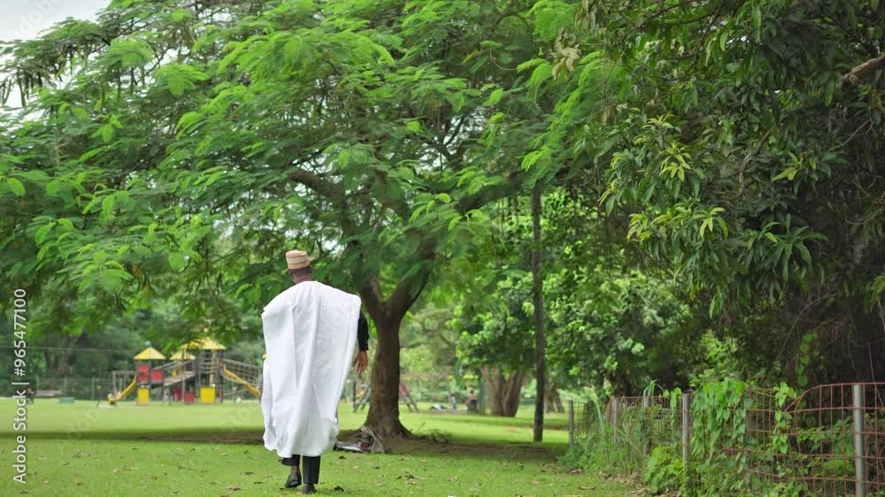 African male in traditional attire walking away from the camera confidently
