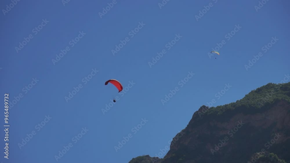 Paragliding, Mountain, Sky - A paraglider flies over a mountain during a sunny day. Paragliding, Mountain, Sky - A paraglider flies over a mountain during a sunny day.