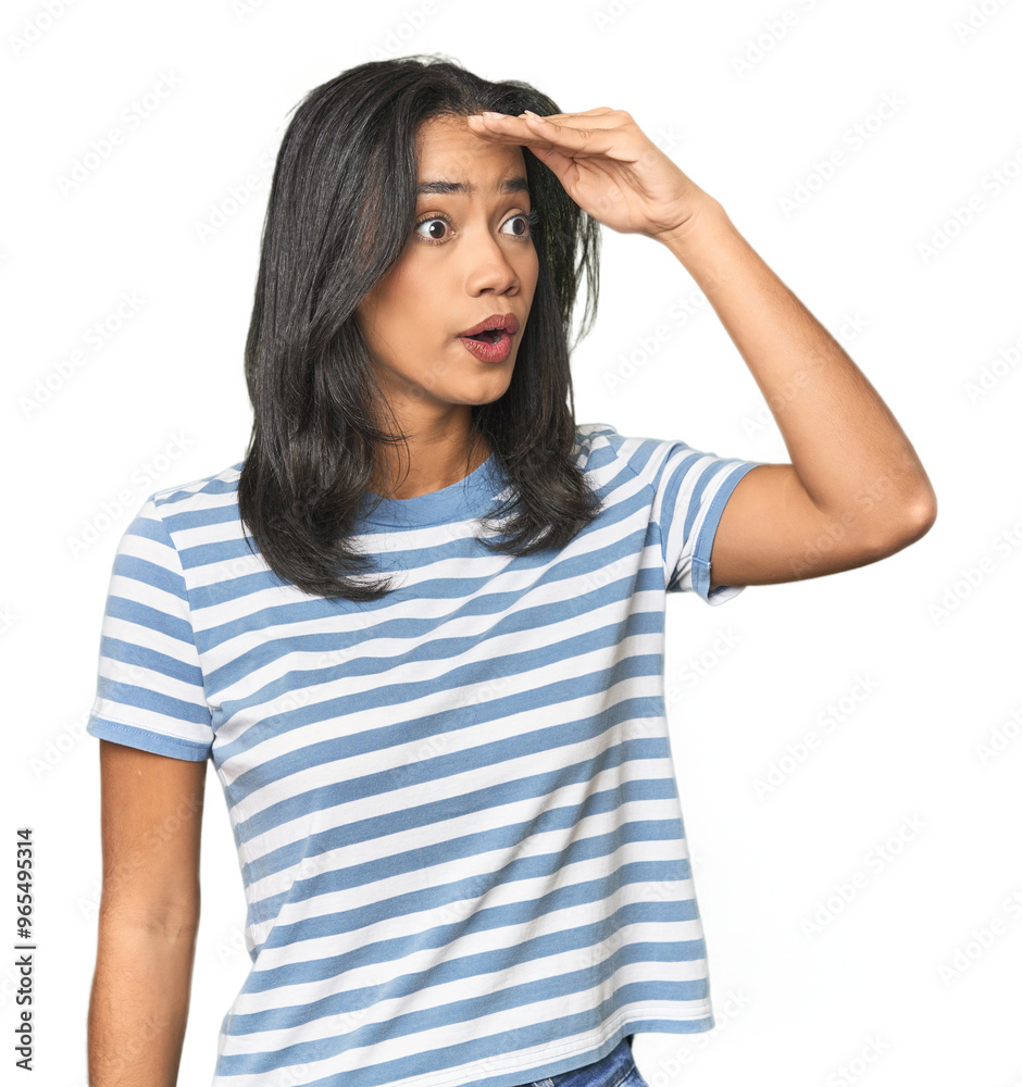 Young Latina posing in studio looking far away keeping hand on forehead. Young Latina posing in studio looking far away keeping hand on forehead.