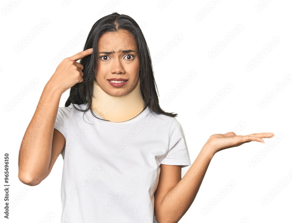 Latina with neck brace in studio holding and showing a product on hand. Latina with neck brace in studio holding and showing a product on hand.